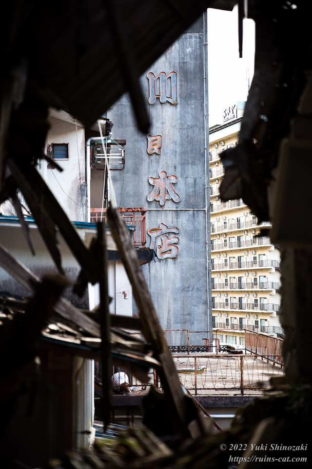 崩れ落ちた壁の隙間から見える「きぬ川館本店」の看板
